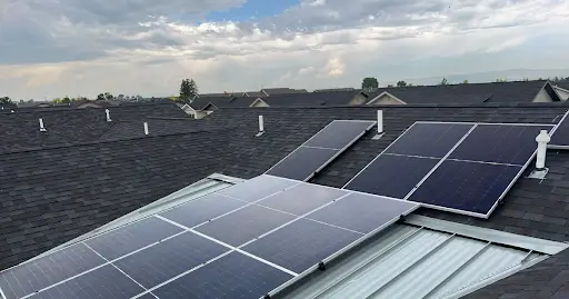 Solar panels installed on a residential roof under a cloudy sky.