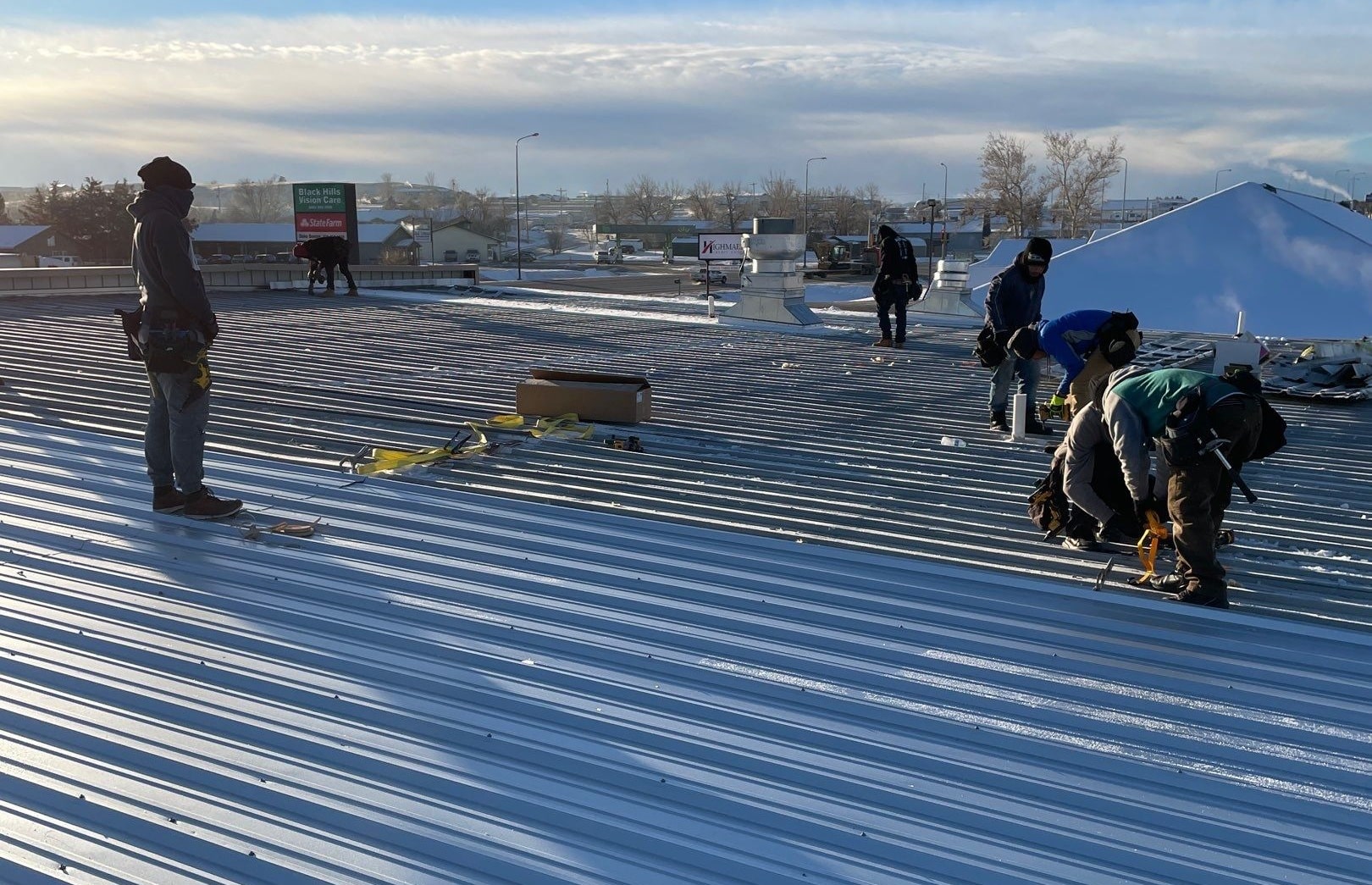 Crew by Roofing & Solar working on a metal roof install, showcasing professional Spearfish Commercial Roofers.